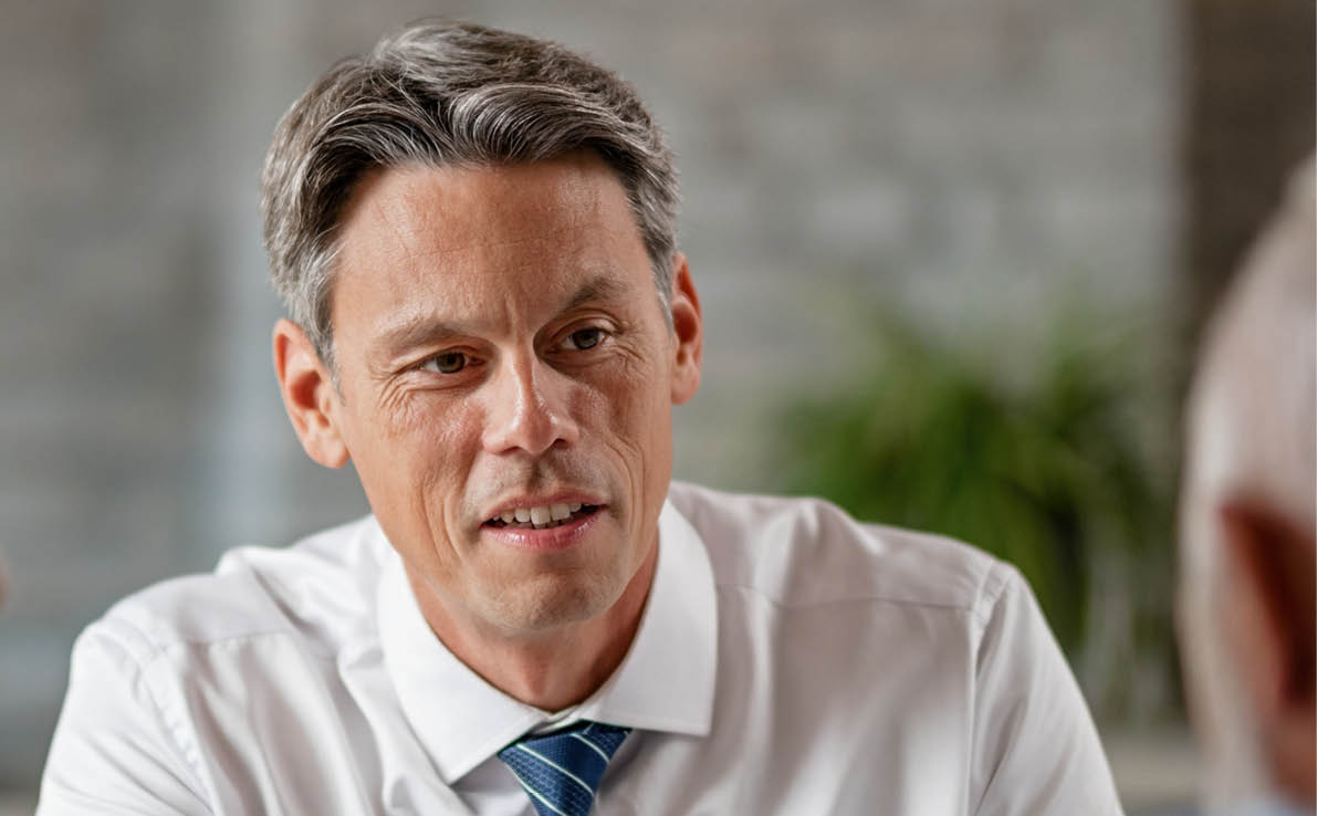 Smiling bank manager showing to his senior customers where to sign on the contract during a meeting in the office.